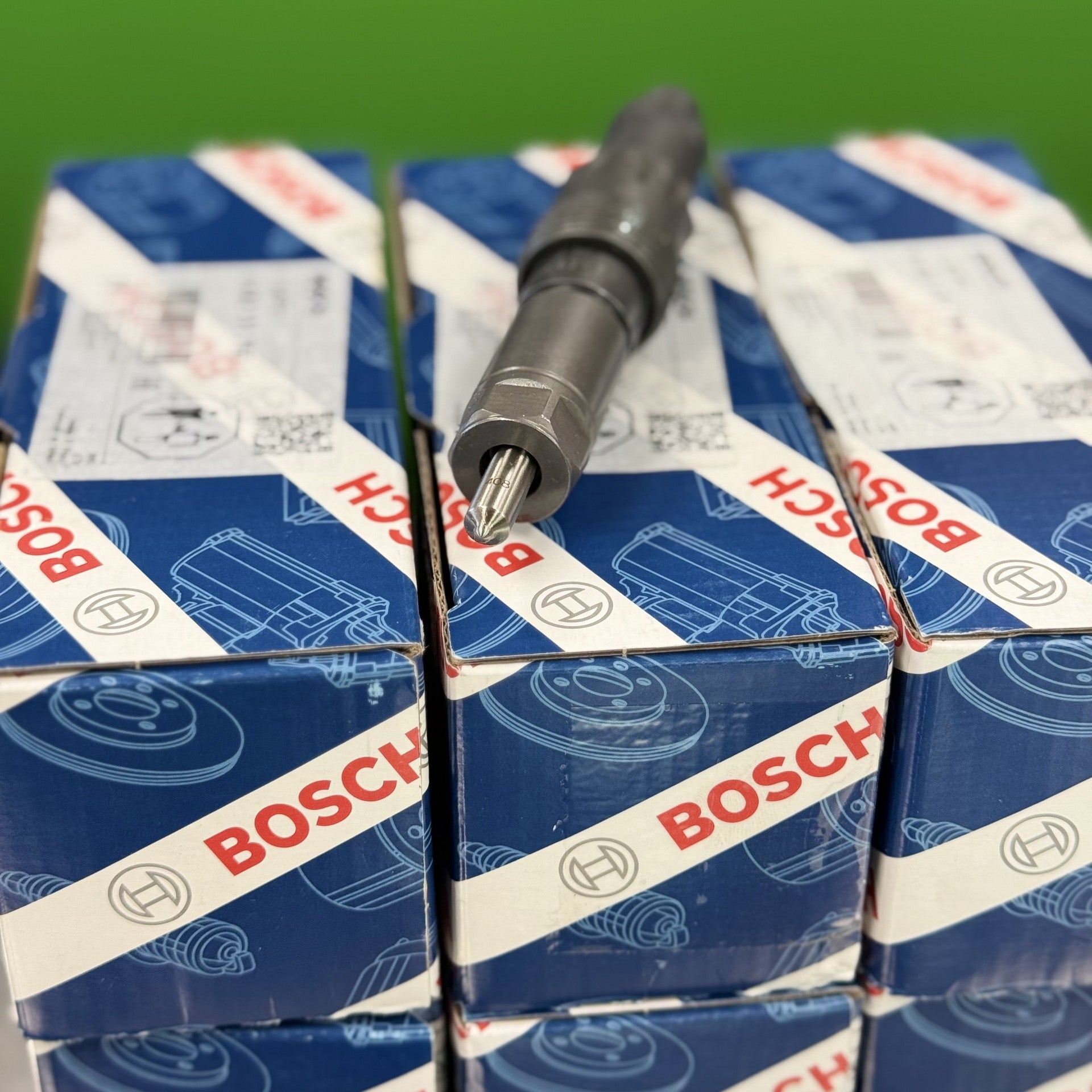 Bosch spark plug boxes on a reflective surface with a green background